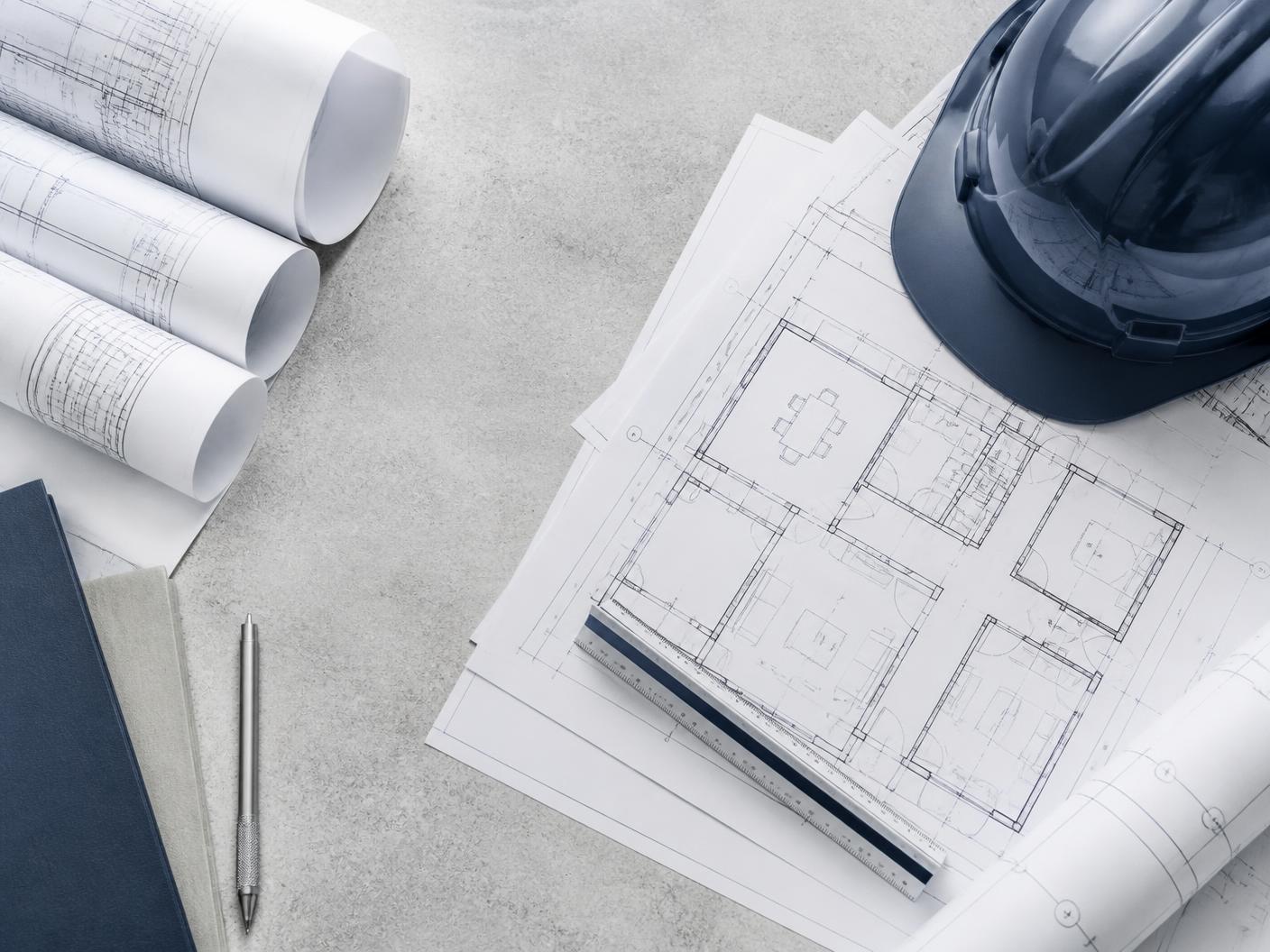 Projetos impressos, escala e capacete sobre superfície de concreto